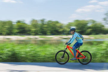 Fototapeta na wymiar A cyclist in a helmet rides a bicycle path, motion blur