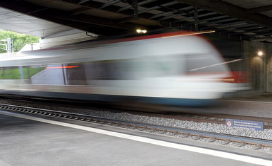 Obraz premium Train speeding through a swiss station captured as a motion blur