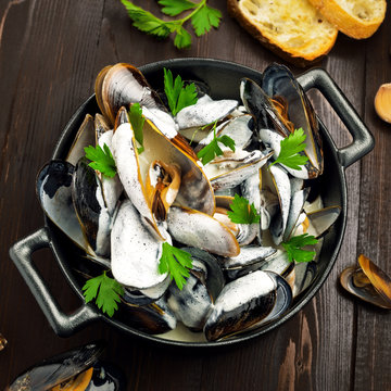 Mussels in a white wine and cream sauce on a table. Classic French meal Moules marini&egrave;re.
