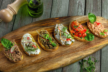 Delicious Italian antipasti bruschetta with tomato, meat pate, olives, cream cheese and tuna salad. Set of tasty appetizer sandwiches. Top view shot.