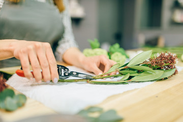 Female florist with pruner in hands makes bouquet