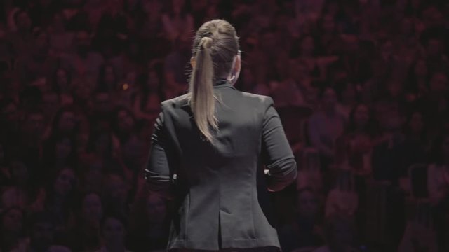 One businesswoman emotional gesturing by hands and says about marketing and management strategies on the education seminar for colleagues working in advertising department. Audience at background