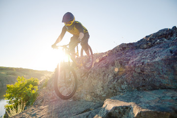 Cyclist Riding the Mountain Bike on the Summer Rocky Trail at the Evening. Extreme Sport and Enduro Cycling Concept.