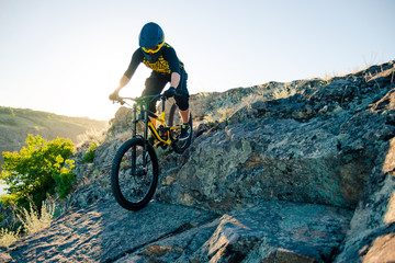 Fototapeta na wymiar Cyclist Riding the Mountain Bike on the Summer Rocky Trail at the Evening. Extreme Sport and Enduro Cycling Concept.
