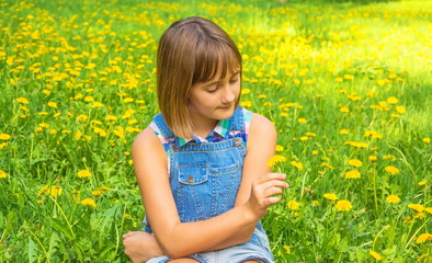 Naklejka na ściany i meble Portrait of a cute teenage girl with a yellow dandelion in her hand