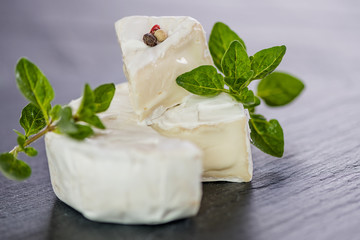 Brie type of cheese. Camembert cheese. Fresh Brie cheese and a slice on a wooden board with nuts, honey and leaves. Italian, French cheese.