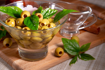Green pitted olives in a glass cup