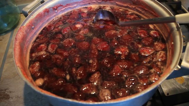 Preparation of strawberry jam. Cook jam. A woman's hand with a ladle neatly stirs the berry homemade jam. Traditional cuisine