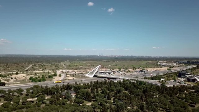 a&eacute;reo drone  volando sobre un bosque y al fondo puente  de la autopista  a6  y veh&iacute;culos circulandoo por la autopista  las rozas de madrid