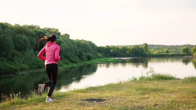 A morning jog in the Park near the pond in the Sunny rays of dawn, the girl is preparing to Mariano and lead a healthy lifestyle