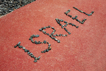 Fototapeta na wymiar The word Israel laid out of stones on an asphalt background