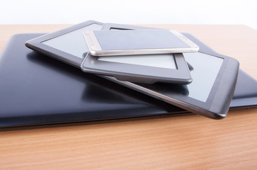 Stack of gadgets on an office desk - notebook, tablets, an ebook reader and a smatphone