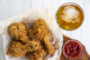 Fried chicken legs with sauce and cold beer, top view. Flat lay.