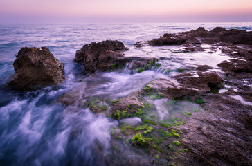 Twilight in a rocky beach full of scum