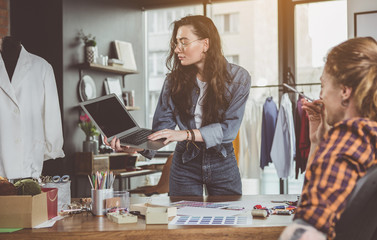Smiling lady demonstrating display of gadget for partner during job. She typing in it