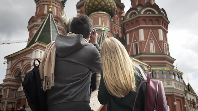 Rear view of a young couple taking pictures of Moscow Saint Basil's Cathedral, Russia. Concept of tourism. Handheld medium shot