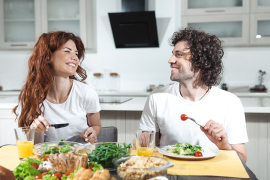 Enjoy your meal, darling. Portrait of happy married couple is eating together in kitchen. They are looking at each other with love and smiling 