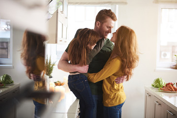 My dearest people. Full length of affectionate man hugging tightly his wife. Small daughter is embracing dad looking at wife with love and care 
