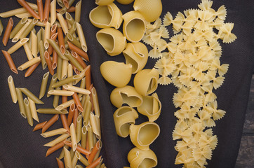 Pasta macaroni concept background. Scattered on the kitchen table different sorts of pasta.