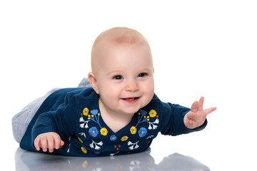 A cute, very little girl is lying on the floor on a white backgr