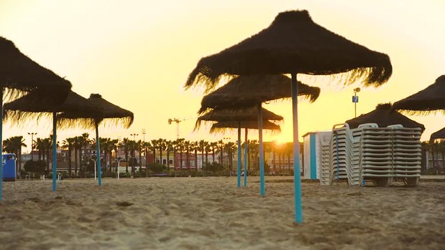 The solar disk disappears behind houses during sunset on the beach of Malvarrosa. Valencia, Spain