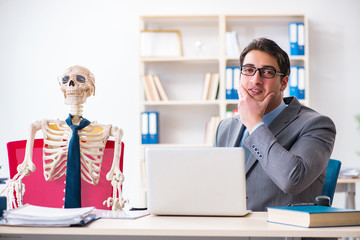 Businessman working with skeleton in office