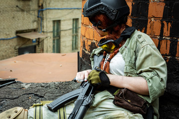 portrait of army girl with rifle in camouflage clothes in urban scene, in hiding