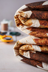 Folded patchwork blanket on white wooden surface on sewing accessories background