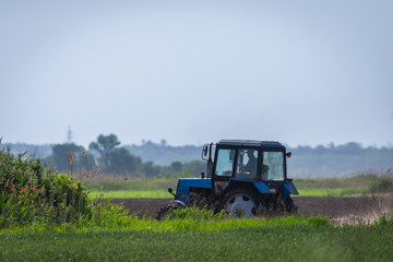 Tractor working on the farm, a modern agricultural transport, a farmer working in the field, fertile land, tractor on a sunset background, cultivation of land, agricultural machine