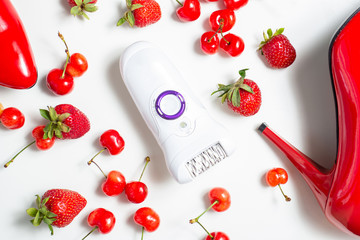 Epilator isolated on white. background with strawberries cherries and female red shoes