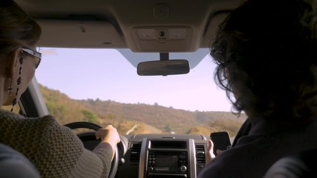 Male passenger using his smart phone while a woman drives in a car
