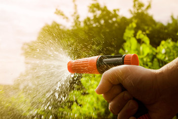 Photo of a male hand holding and working with water spray gun on sunny day.
