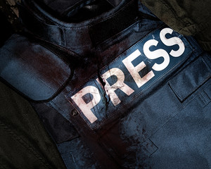 Photo of a press journalist armor war protective vest in blood splatter depicting mass media war victims.