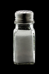 A glass shaker of table salt isolated on black background