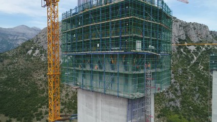 Tilting aerial view of pillar of new bridge and highway, built by a Chinese state owned company in Montenegro