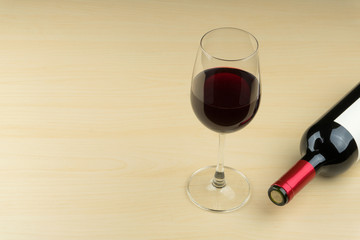 a glass of red wine and wine bottle on the wooden table