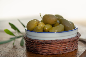 Bowl with green olives served as snack outdoor in olive tree garden