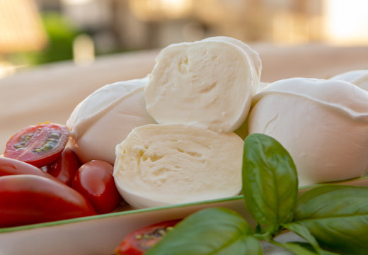 Fresh soft Italian white cheese mozzarella buffalo, original from Campania, Paestrum and Foggia regions, South Italy, served with tomatoes and fresh basil