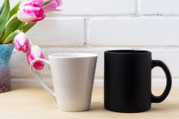 Black coffee cup and white latte mug mockup with magenta tulip