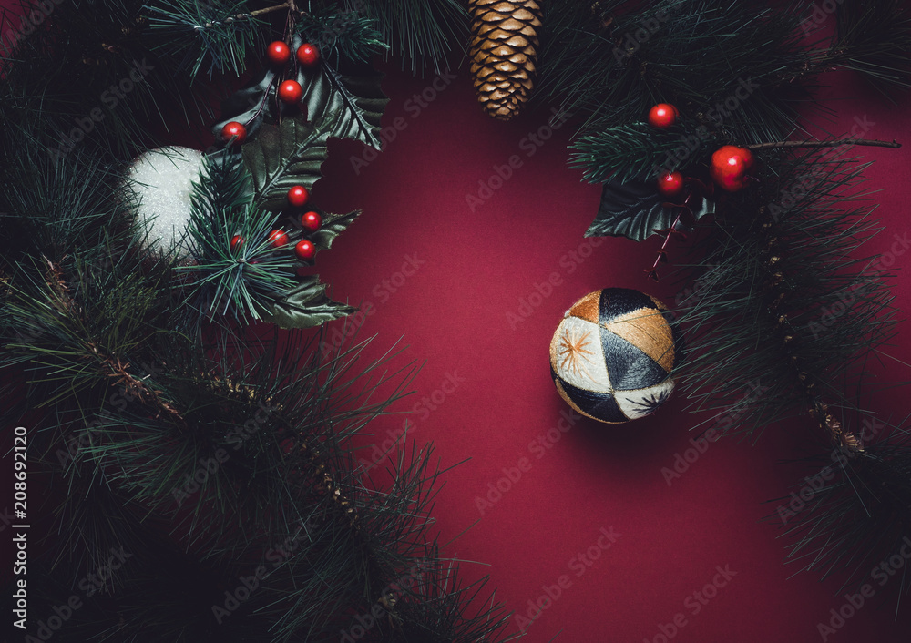 Poster christmas ball and fir branches for wreath with cherry and pine cone on red table background. winter