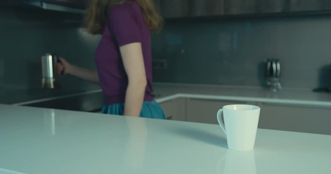 Young woman in kitchen pouring a cup of coffee