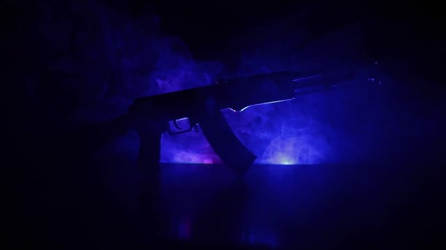 Silhouette of assault rifle on toned foggy background. War or antiterrorism concept. Russian military weapon on table. Slider shot
