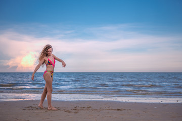 Fototapeta na wymiar Happy woman with long blonde curly hair on the beach with enjoying and refreshing, summer beach relaxing time concept.