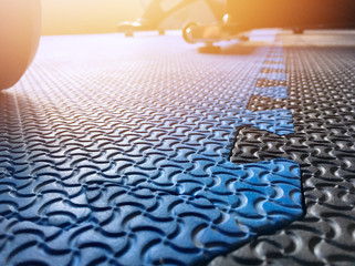The blue rubber gym floor with the shadow of dumbell behind.