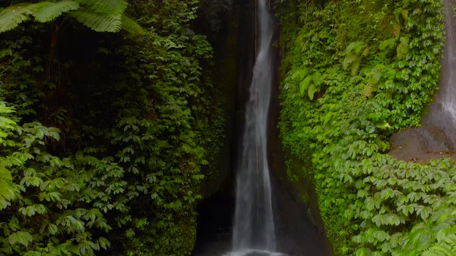Aerial View of the Leke Leke waterfall in jungles of Bali, Indonesia. Camera tilts up