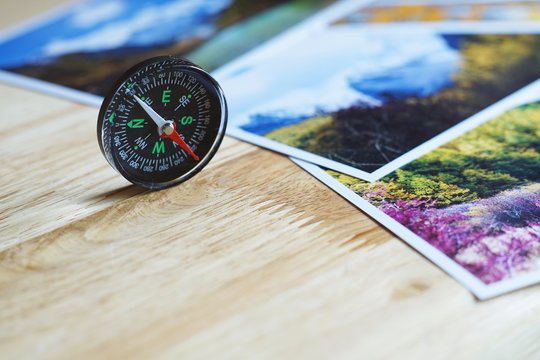 Compass on blur nature photograph of popular tourist destination in autumn background, China traveling concept