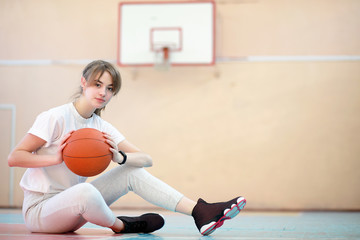 Naklejka premium Girl in the gym playing a basketball