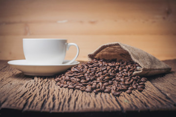 Coffee cup with coffee beans on wood table.