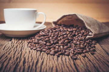 Coffee cup with coffee beans on wood table.