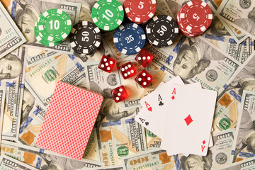 Dice, playing cards and poker chips on the background of scattered 100 bills. Winning concept
